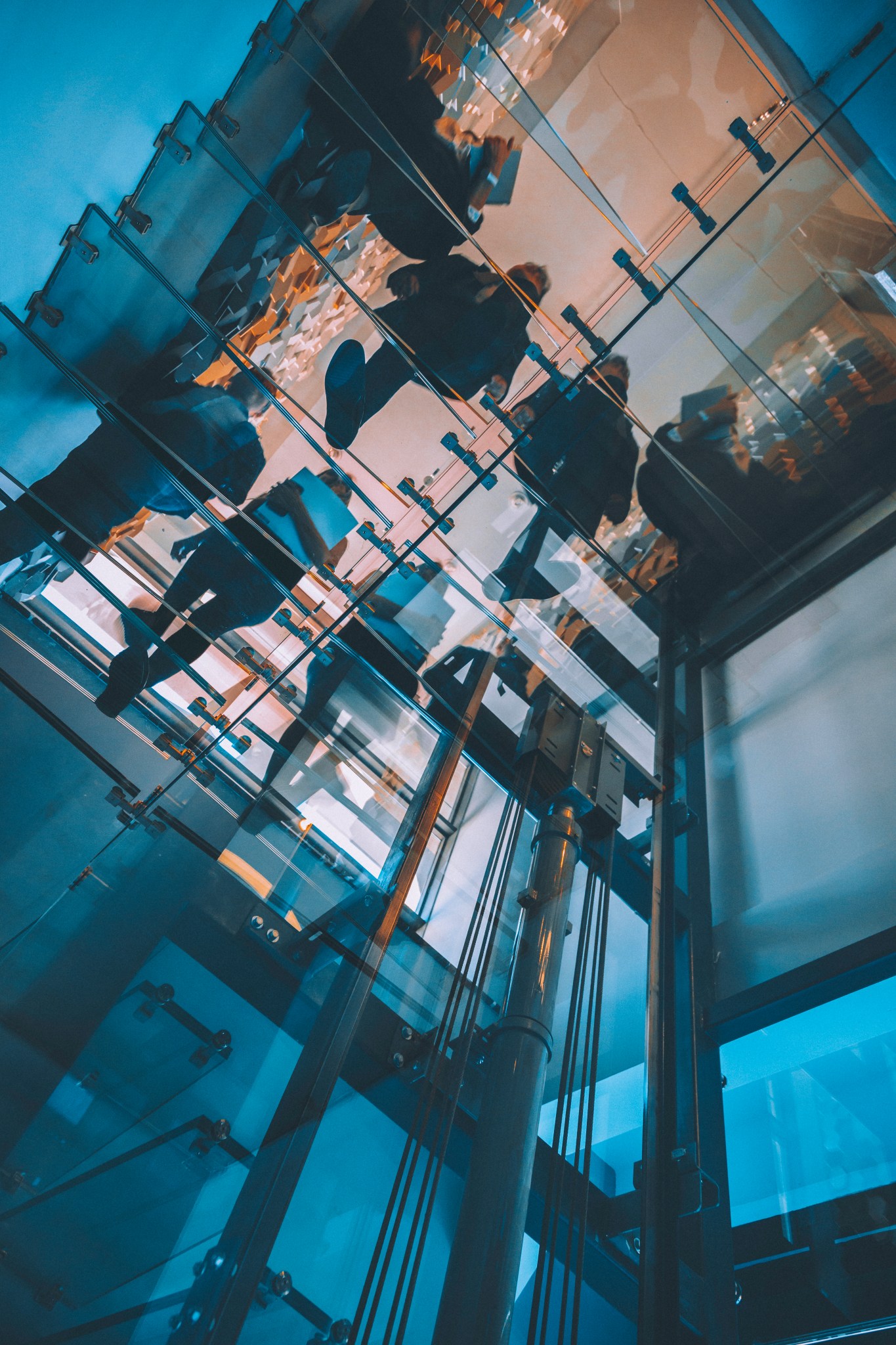 Motion blur of people walking on transparent glass spiral staircase