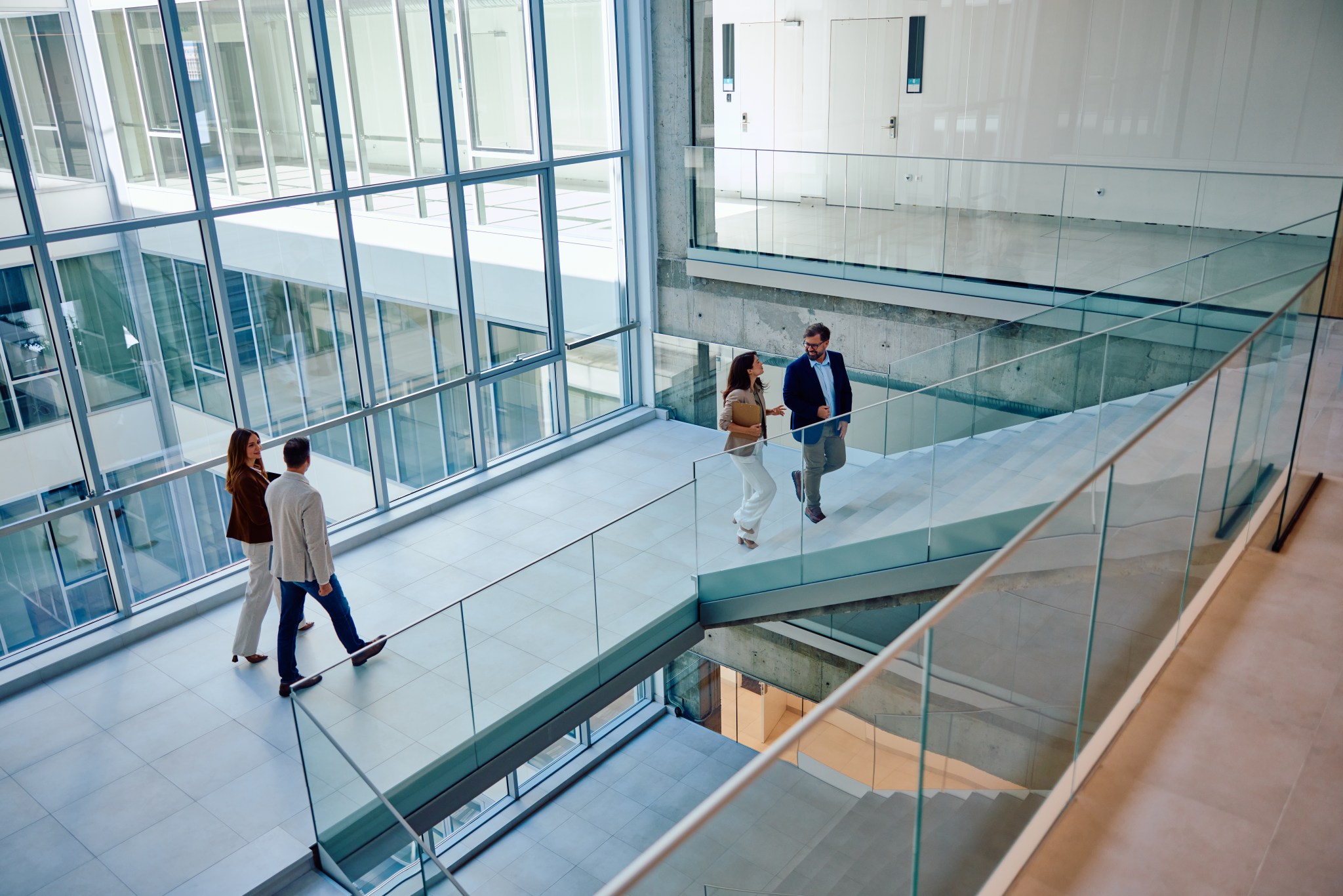 Group of adults in professional attire walking inside a modern corporate office building